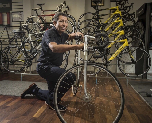 Maurice Burton, De Ver Cycles Maurice Burton kneeling with a bicycle in the De Ver Cycles shop